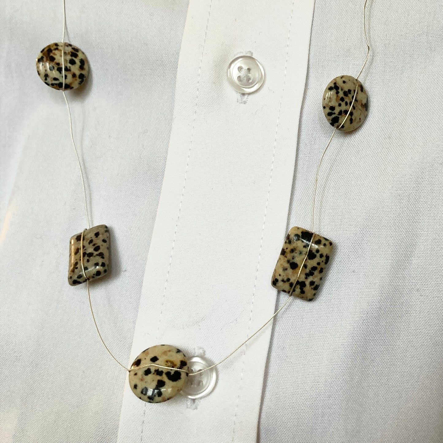 ECU of Dalmation Discs and Rectangles against a white button shirt 